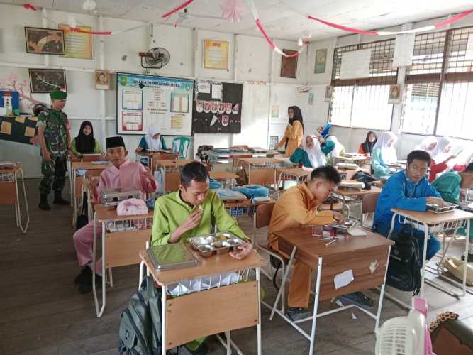 Babinsa Serda Ronal Manalu mendampingi penyaluran 2.671 porsi Makan Bergizi Gratis (MBG) di wilayah Tembilahan Hulu.