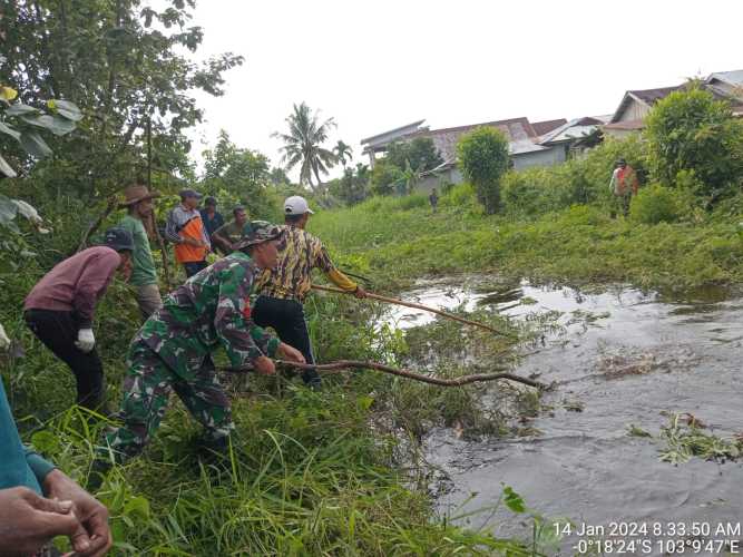 Ajak Warga Gotong Royong Sertu Deni sutrisno dan Warga Sungai Beringin Bersihkan Parit Untuk Antisipasi Banjir