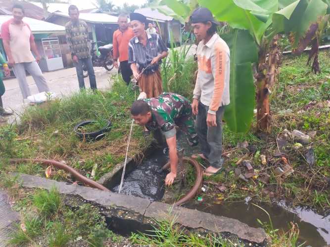 Memanfaatkan Waktu Pagi,Babinsa Bersihkan Drainase Pemukiman Warga