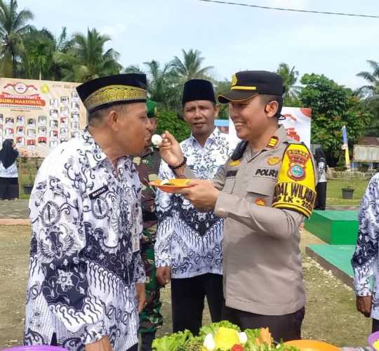 Kapolsek Kempas Berikan Potongan Tumpeng kepada Kepala Sekolah pada Peringatan HGN.